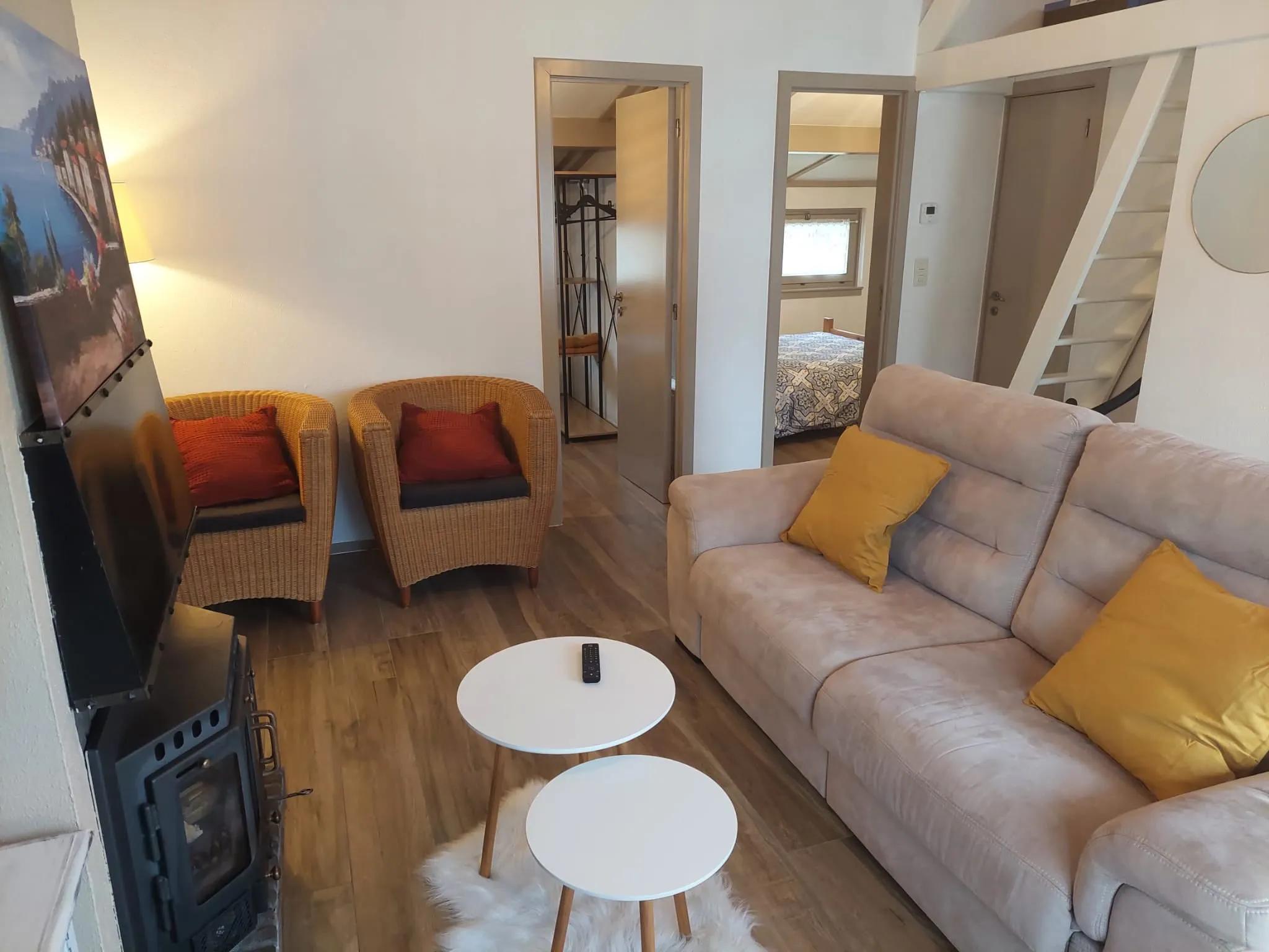 Wohnzimmer mit beigem Sofa, Korbsesseln und zwei weißen Couchtischen