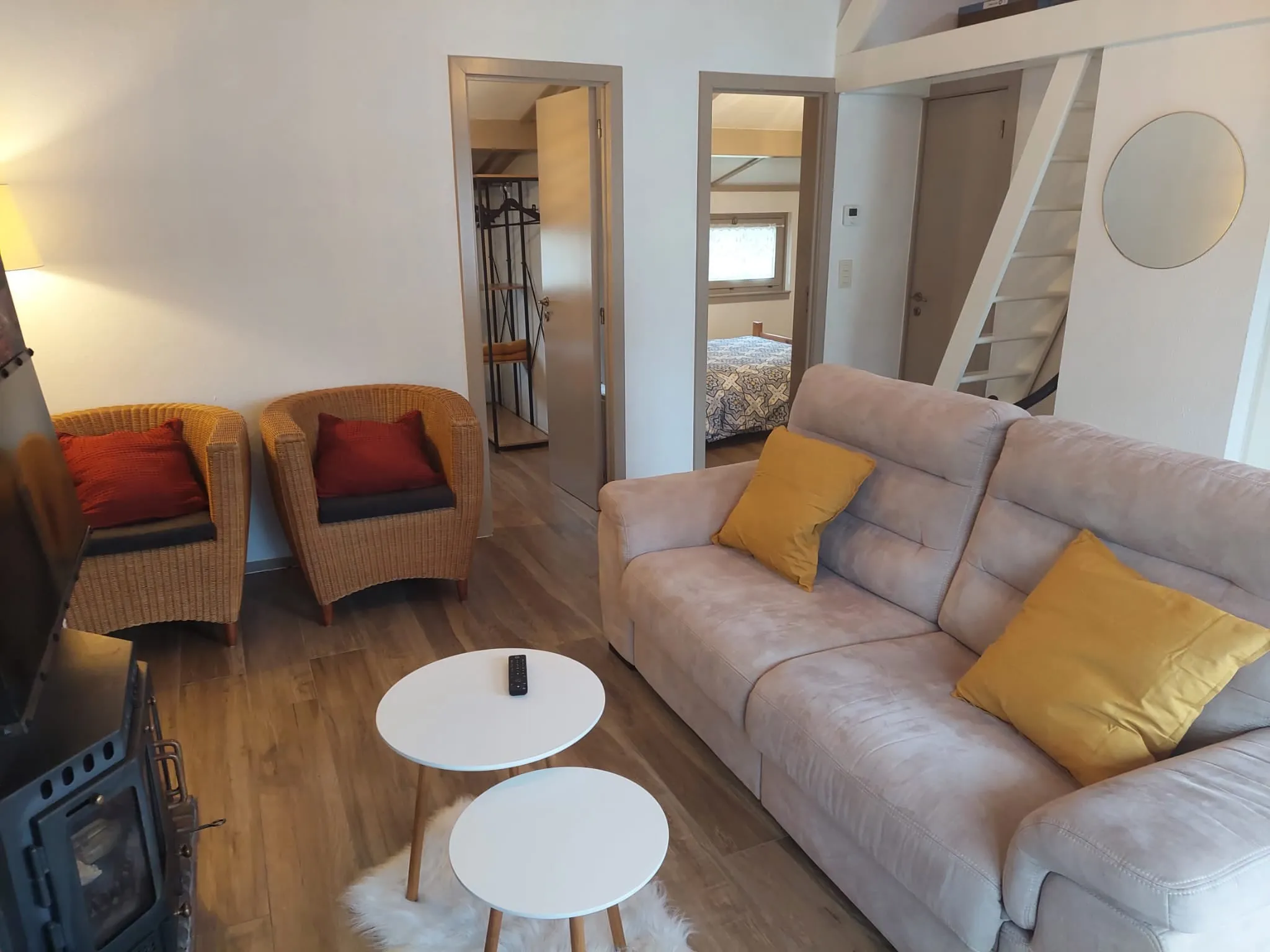 Sitzecke mit beigem Sofa mit gelben Kissen und Korbsesseln