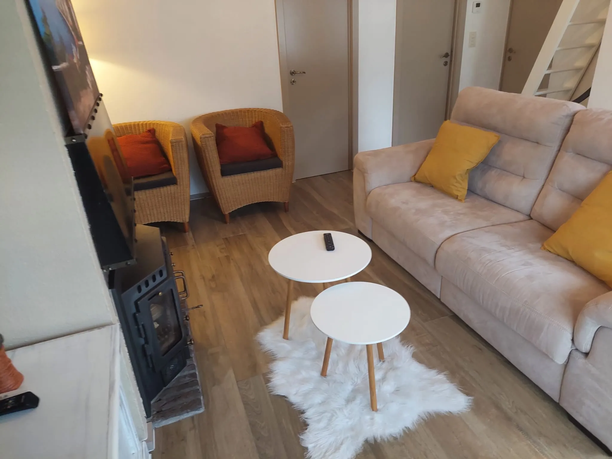 Zwei weiße Couchtische auf einem weißen Schaffell vor dem Sofa