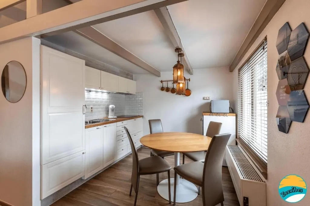 Keuken met witte kasten en een ronde houten tafel met stoelen