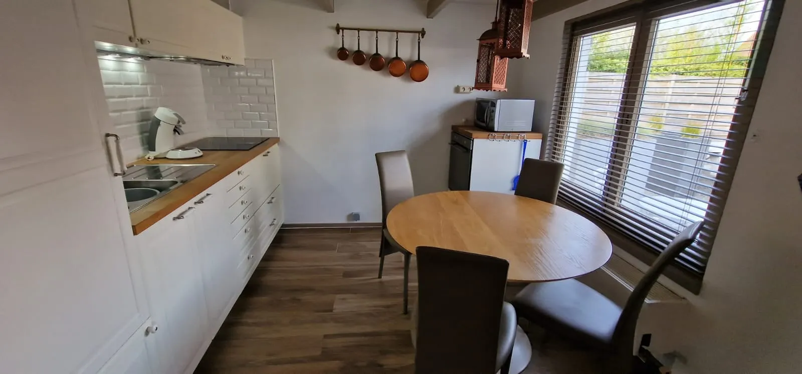 Küche mit rundem Holzesstisch und einem Fenster mit Jalousien