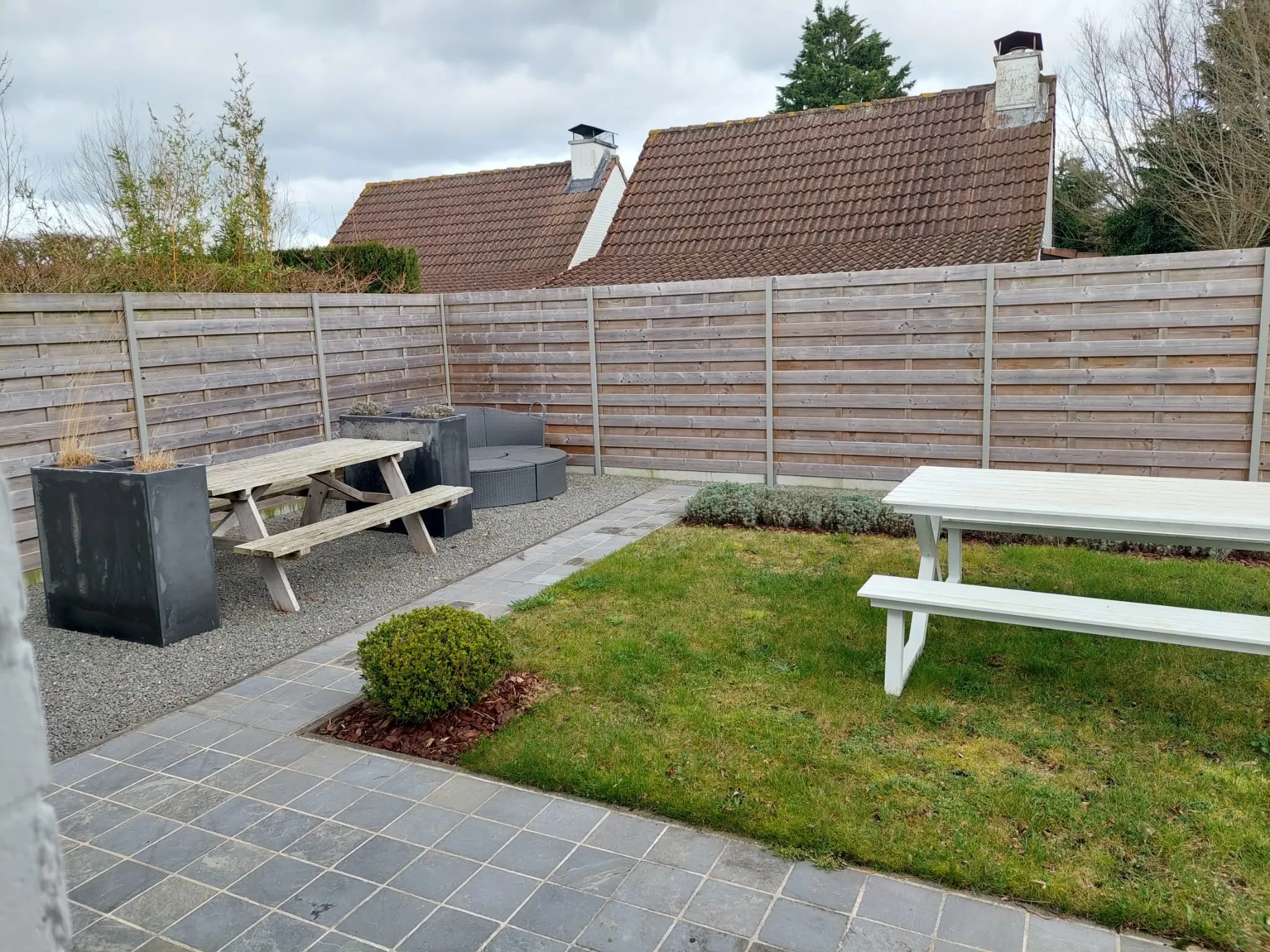 Gartenecke mit Picknicktisch vor dem hohen Holzzaun