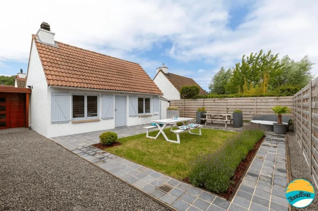 Vorderseite des weißen Hauses mit dem umzäunten Garten