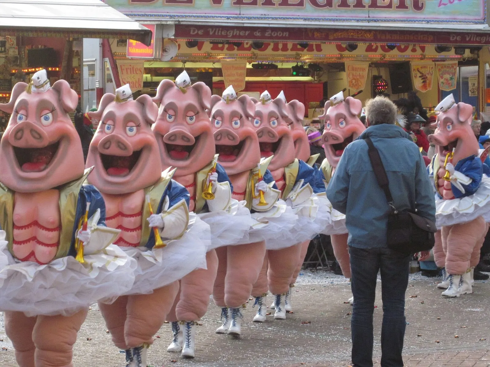 Carnavalisten verkleed als roze varkens met tutu’s lopen in een optocht