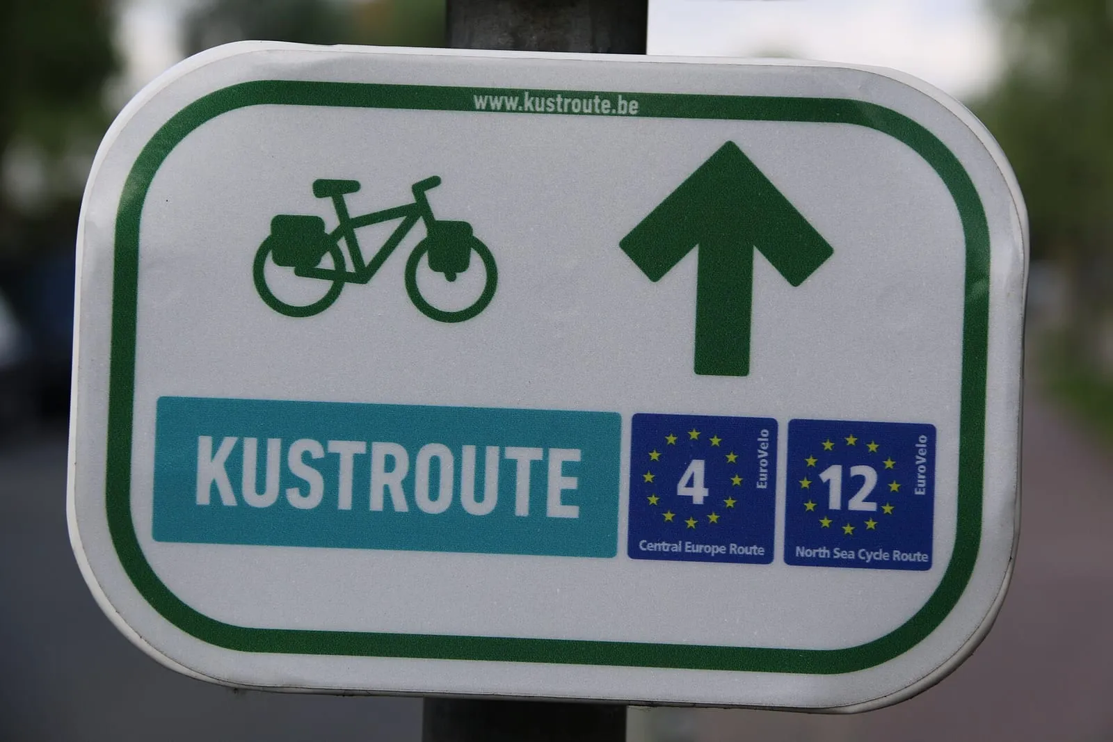Bordje van de Kustroute met een fietssymbool en een pijl rechtdoor