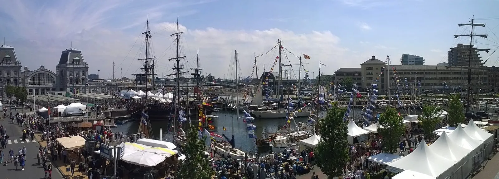 Panoramafoto van de haven van Oostende met hoge zeilschepen en witte tenten langs de kade