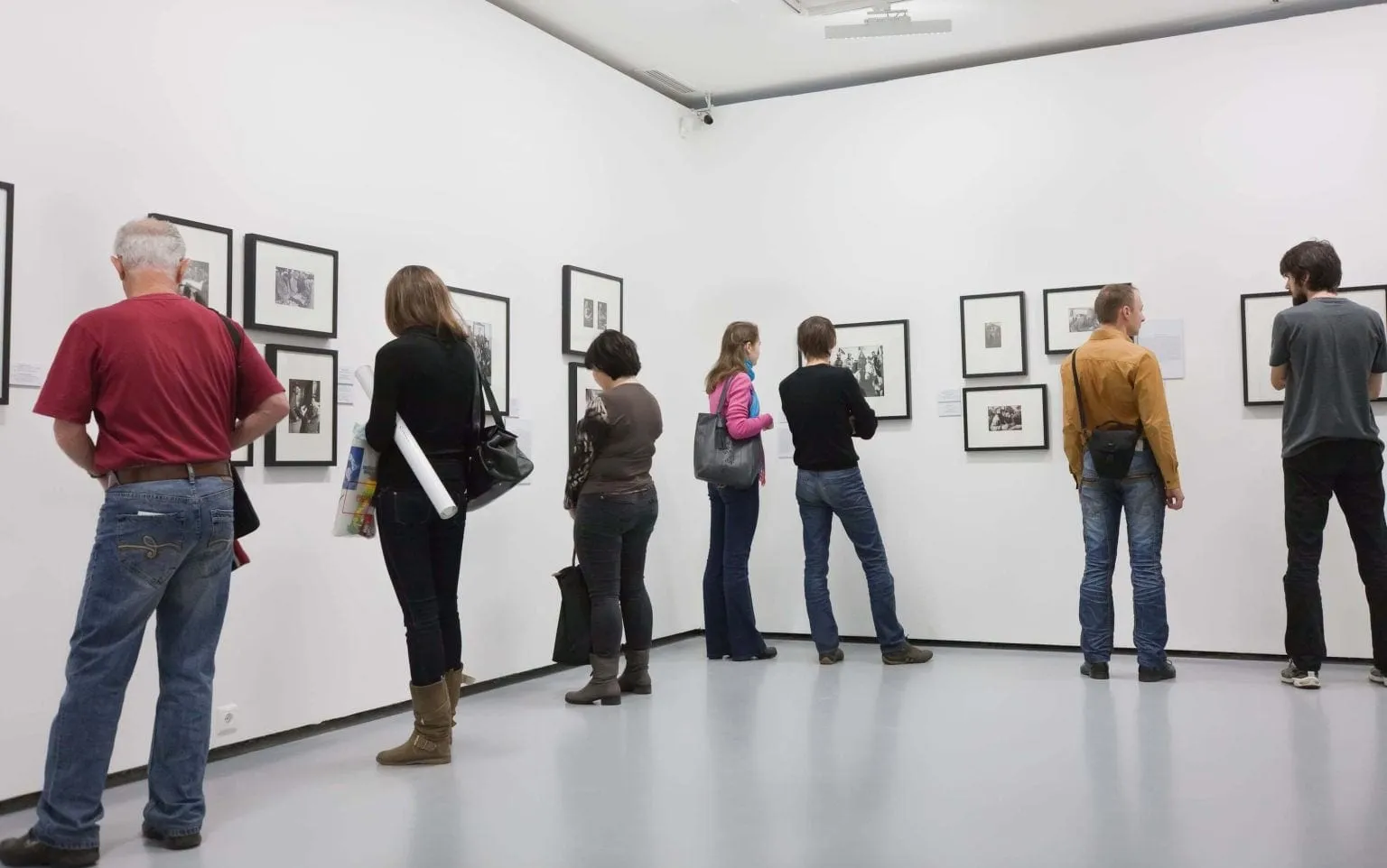 Bezoekers bekijken ingelijste werken in een witte museumzaal